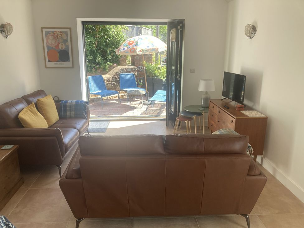 A living room with a sofa and television at Jams in Lympstone