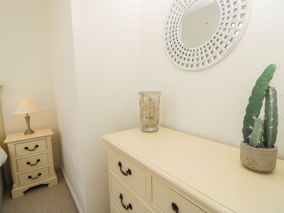 A bedroom with a dresser, bedside table, lamp and plants at Vermont 4 Yarmouth