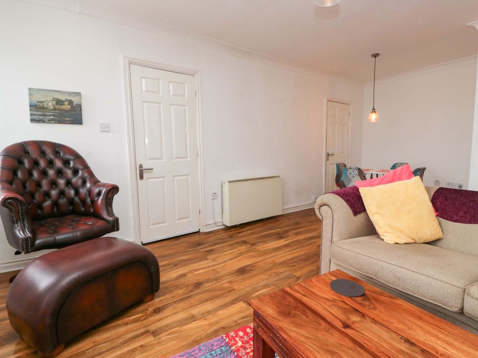 A living room with furniture including a chair, ottoman, and sofa at Duncan Square in Whitehaven