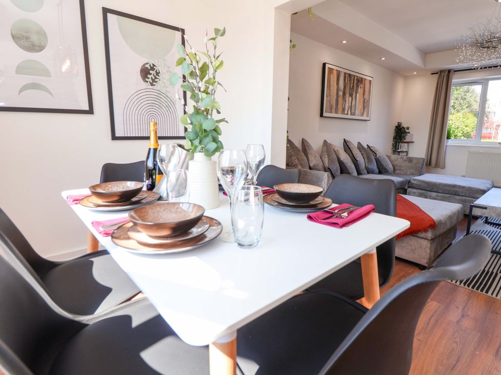A dining room with a table set for meals and a couch at 11 Coniston Road Chester