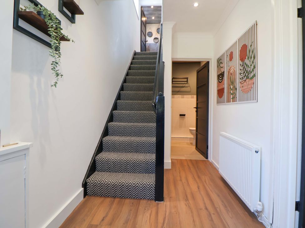 A hallway with a staircase and artwork on the wall at 11 Coniston Road Chester