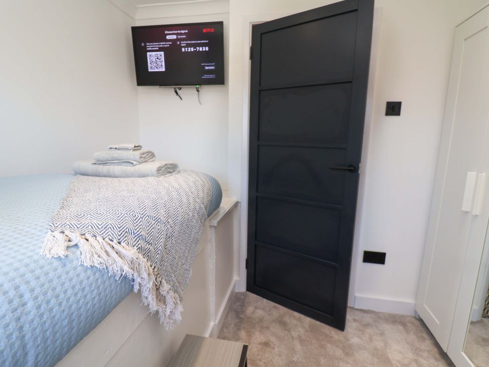 A bedroom with a bed, TV, and door at 11 Coniston Road Chester
