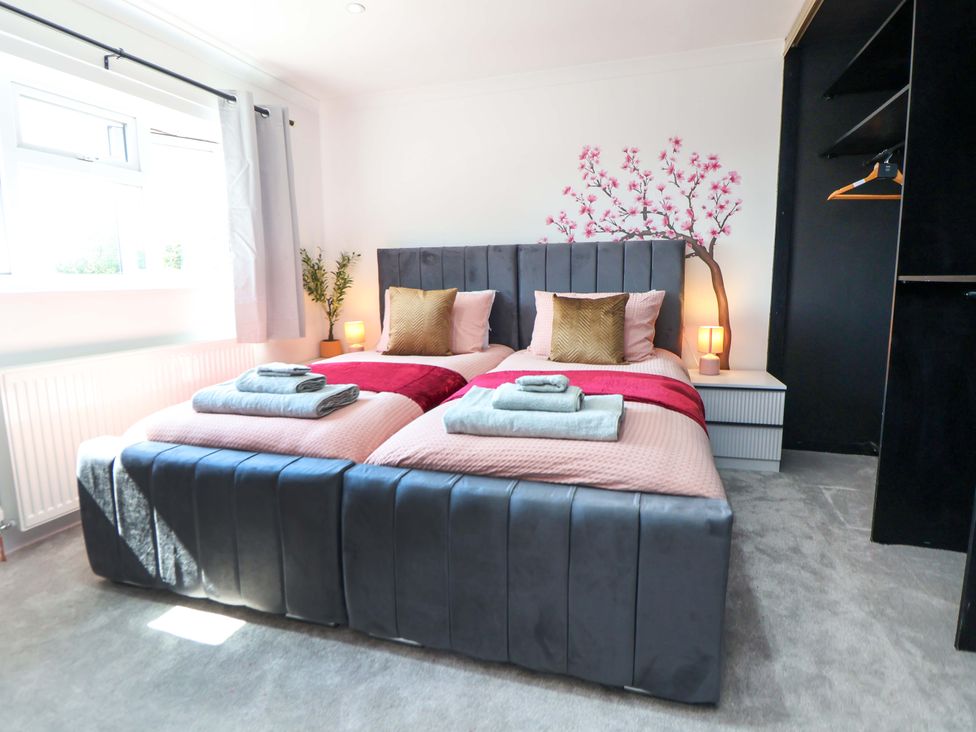 A bedroom with two beds and a nightstand at 11 Coniston Road in Chester