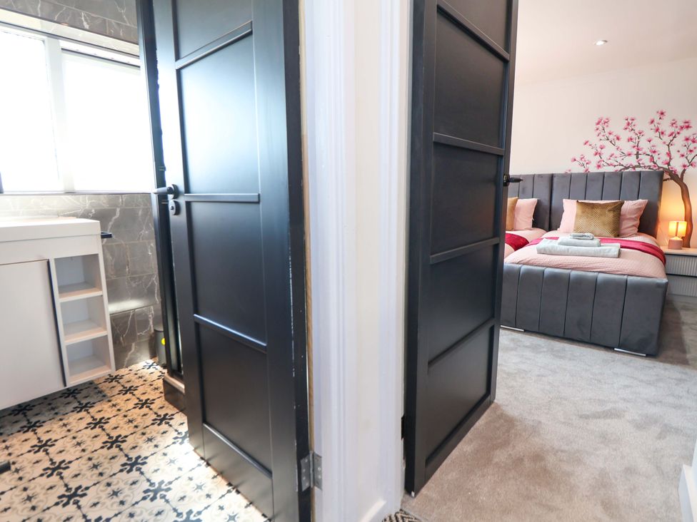 A bathroom with sink and a bedroom with a bed at 11 Coniston Road Chester