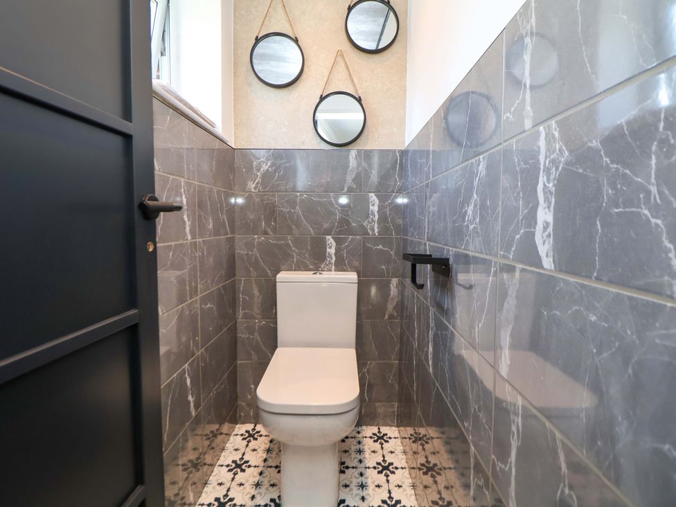 A bathroom with a toilet and mirrors at 11 Coniston Road Chester