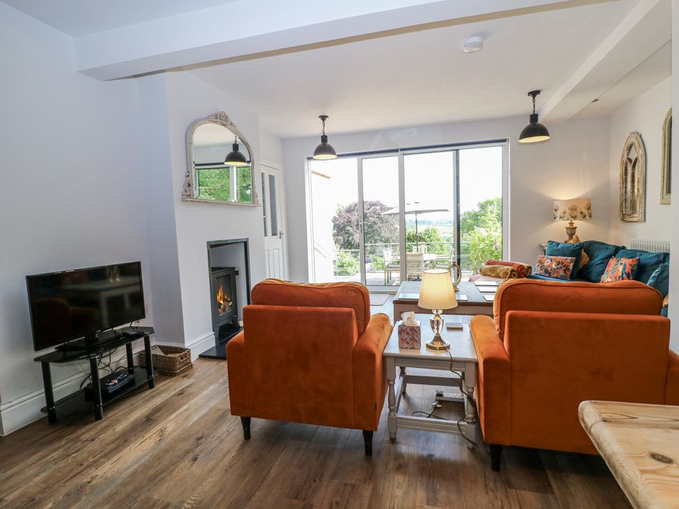 A living room with a fireplace, tv, and floor-to-ceiling windows at The View @ Orchard View in Hognaston
