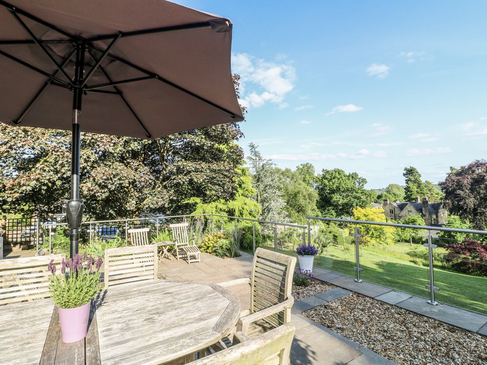 An outdoor area with a table and chairs under an umbrella at The View @ Orchard View in Hognaston