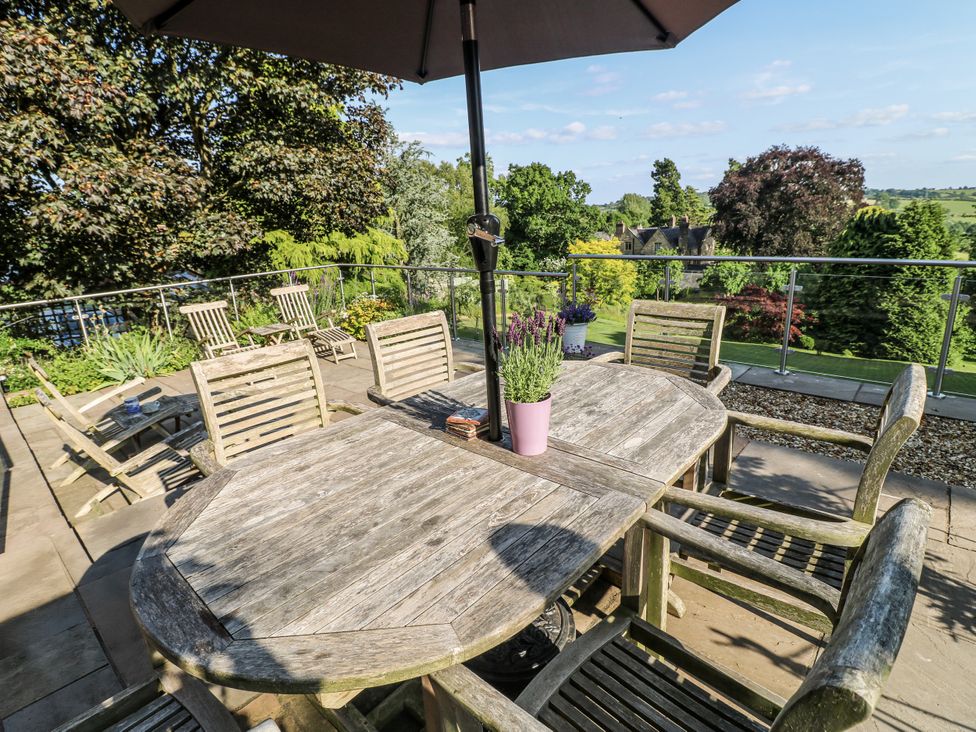 A patio area with a wooden table and chairs at The View @ Orchard View in Hognaston