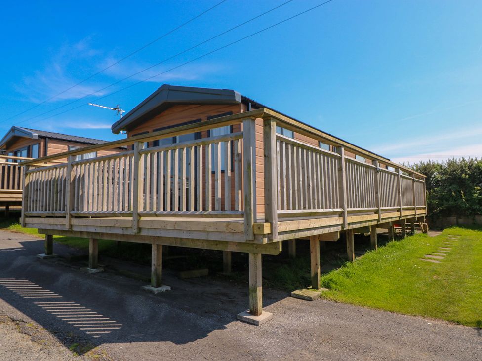 A cabin with a wooden deck in an outdoor area at No 13 Broadfield Farm Holiday Park Saundersfoot