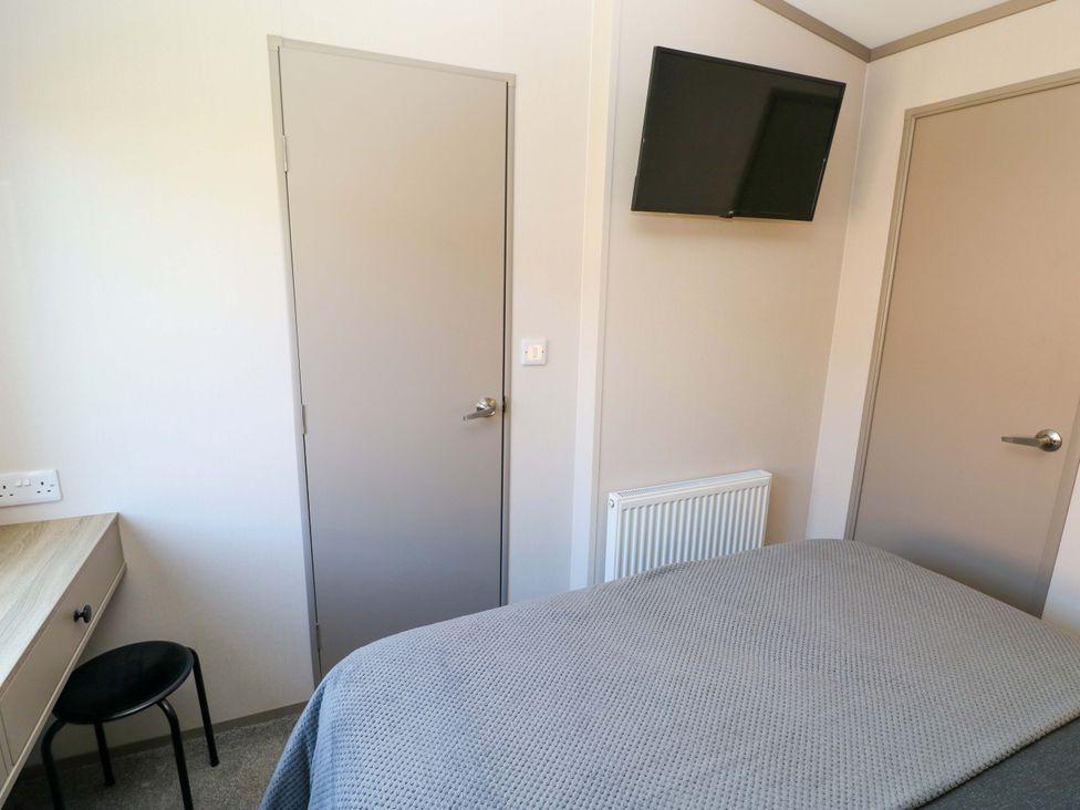 A bedroom with a bed and a television at No 13 Broadfield Farm Holiday Park, Saundersfoot