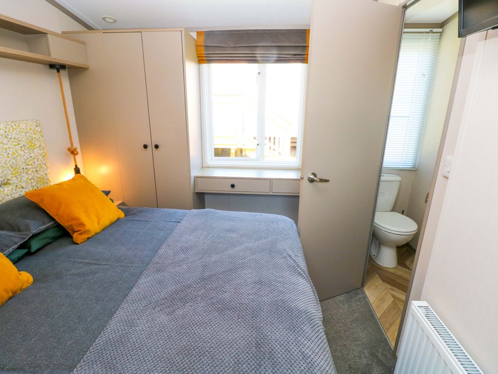 A bedroom with a bed and wardrobe at No 13 Broadfield Farm Holiday Park in Saundersfoot