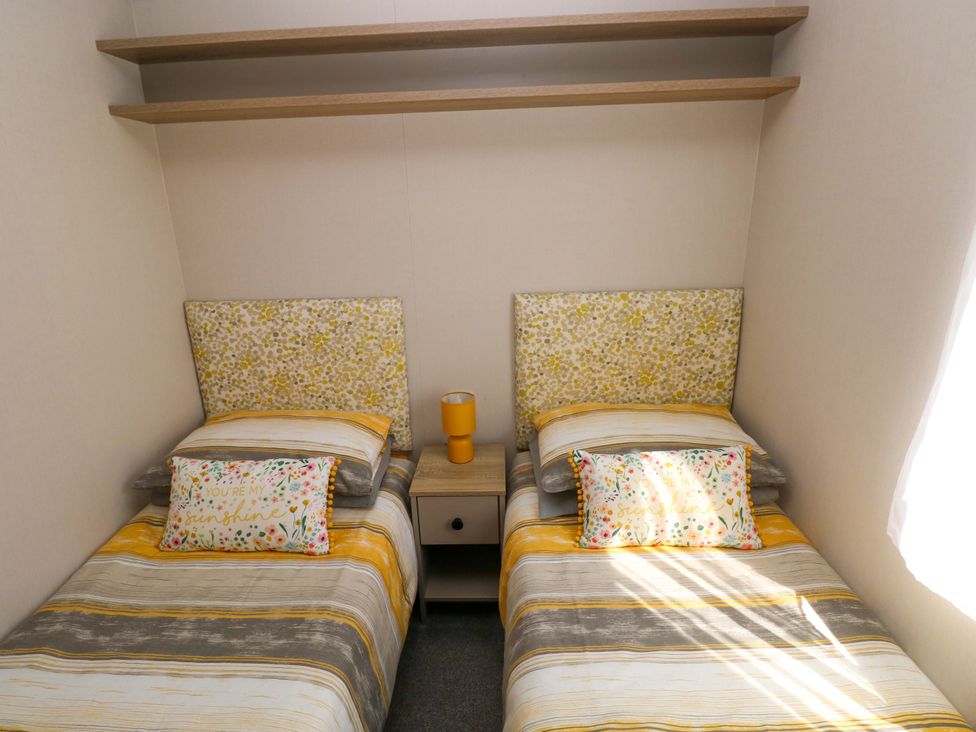 A bedroom with two beds and a bedside table at No 13 Broadfield Farm Holiday Park, Saundersfoot
