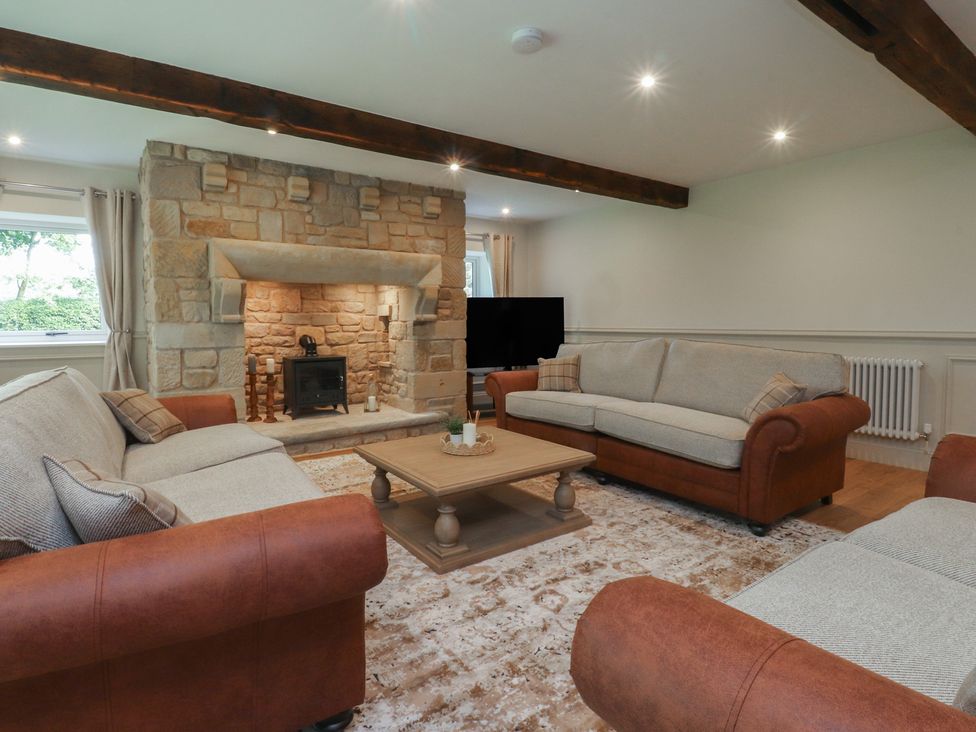 A living room with a stone fireplace and sofas at Alston House