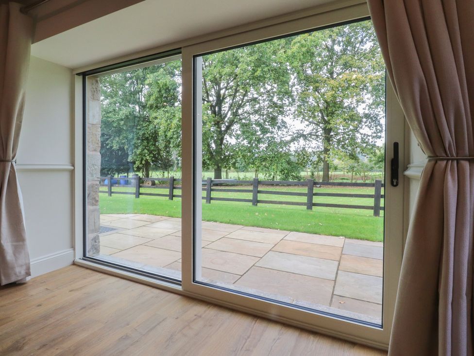 A living room with a large window overlooking a patio and garden at Alston House