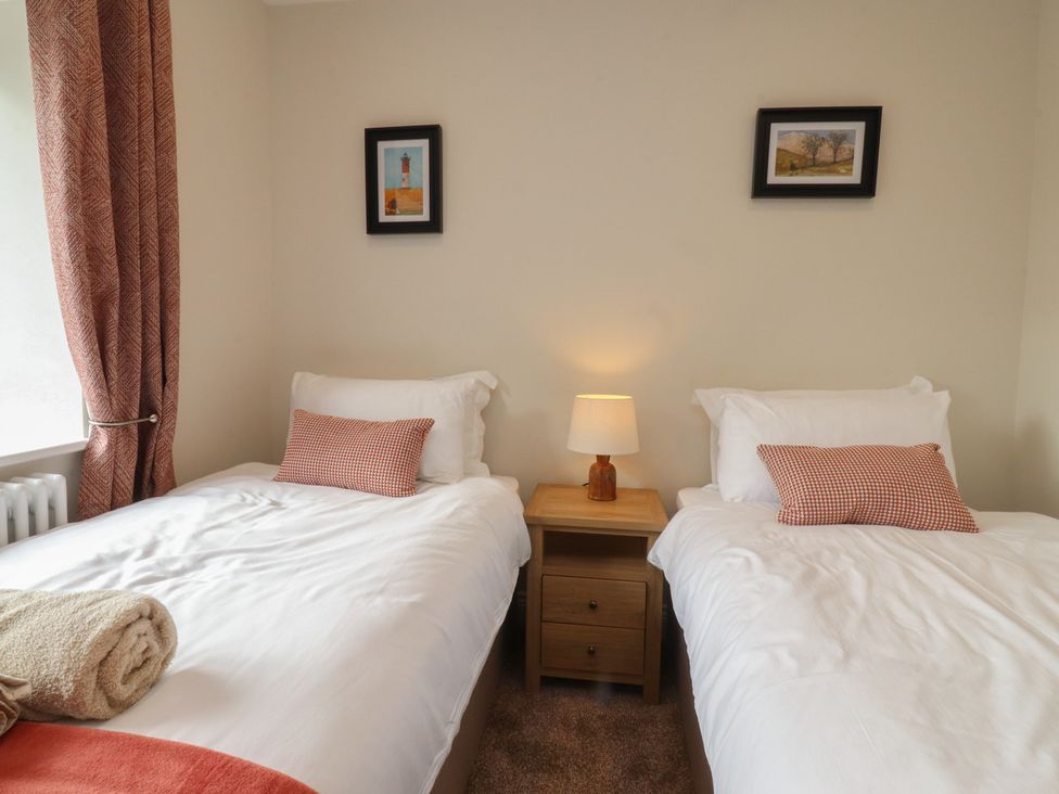 A bedroom with two beds and a bedside table at Alston House