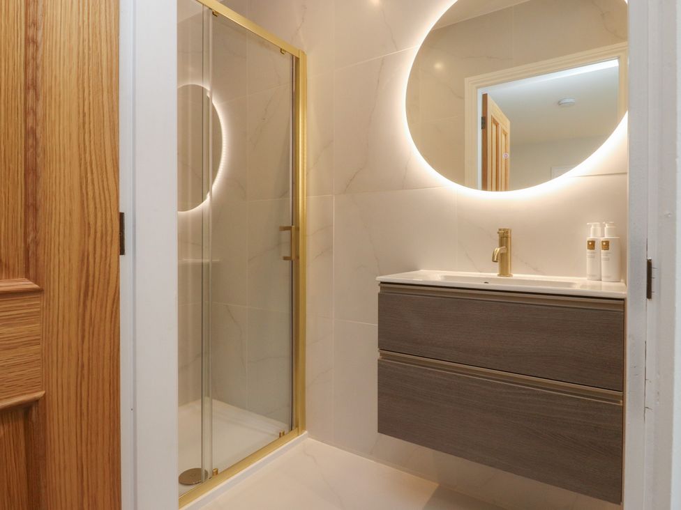 A bathroom with a shower, sink, and mirror at Alston House