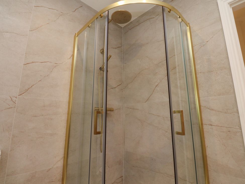 A shower with glass doors and gold trim at Alston House