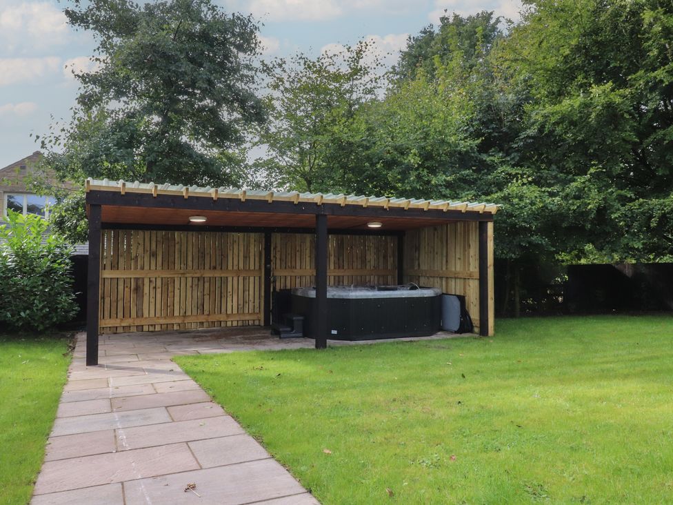 A hot tub in a sheltered area with grass and trees at Alston House
