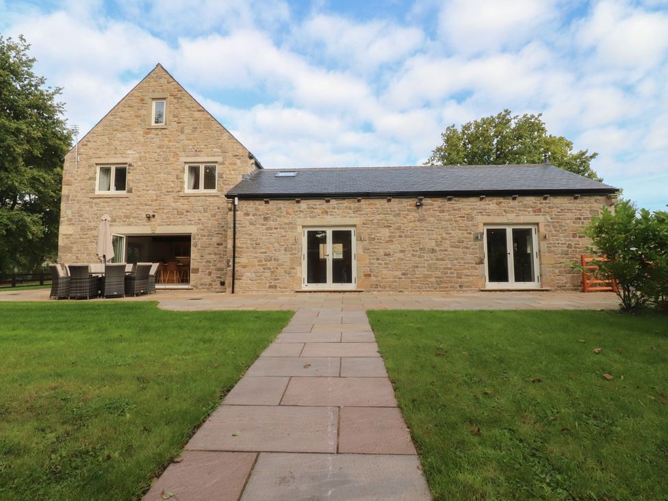 A two-story stone house with a patio and lawn at Alston House