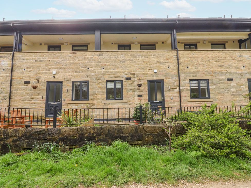 An outdoor view of a stone building with windows and a door at Number 7 Canalside Skipton
