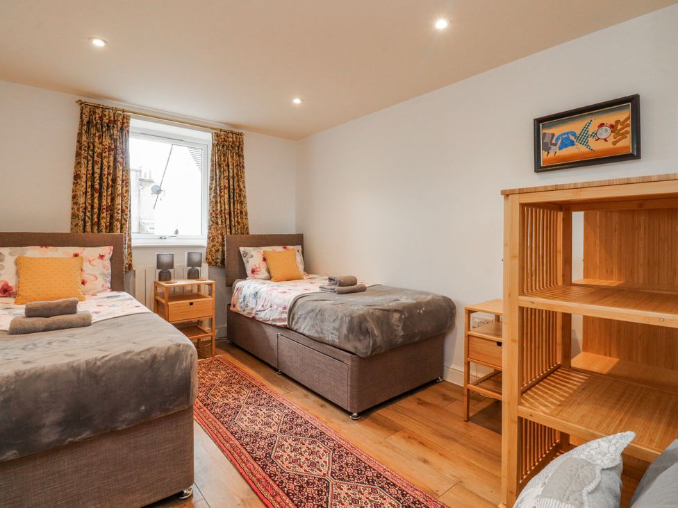 A bedroom with two beds and a wooden shelf at Number 7 Canalside in Skipton