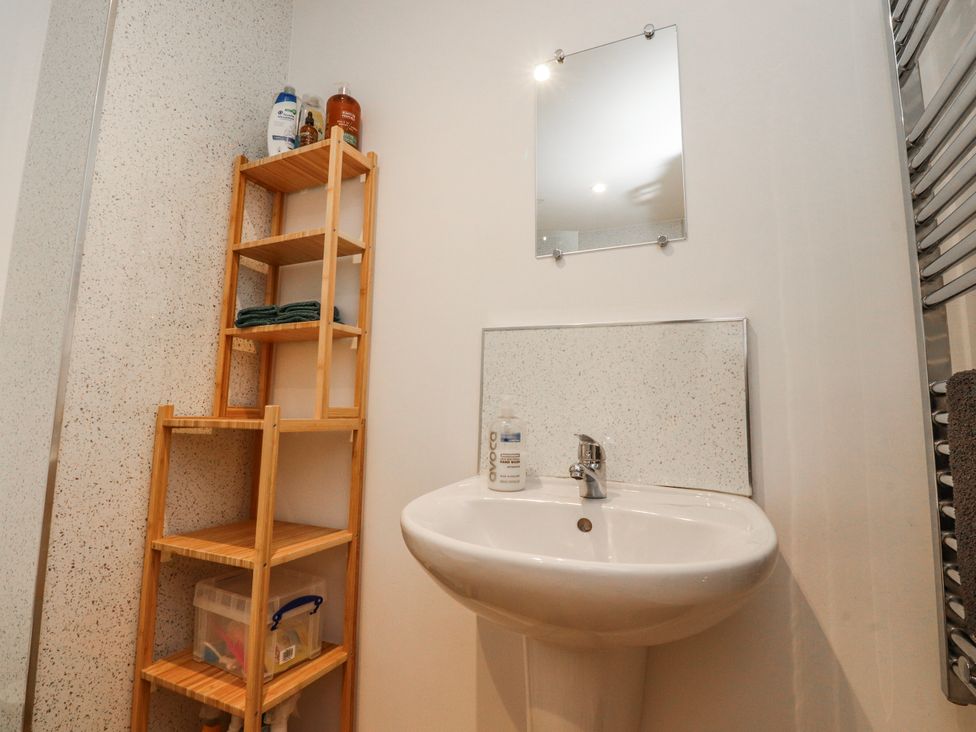 A bathroom with a sink and shelf storing towels and toiletries at Number 7 Canalside in Skipton