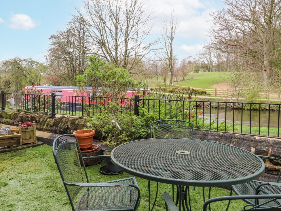 A garden with a table and chairs overlooking a canal at Number 7 Canalside in Skipton