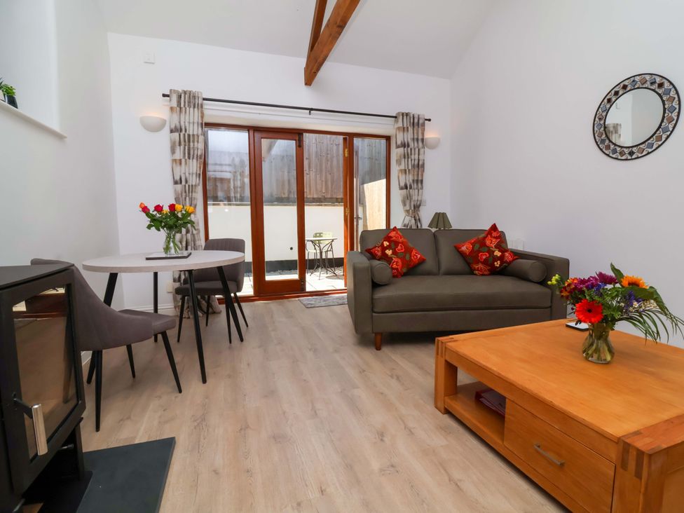 A living room with a sofa, coffee table and dining area at Hedgehog Highway Parkham