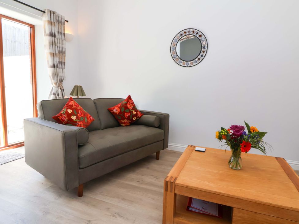 A living room with a sofa and a flower vase at Hedgehog Highway in Parkham