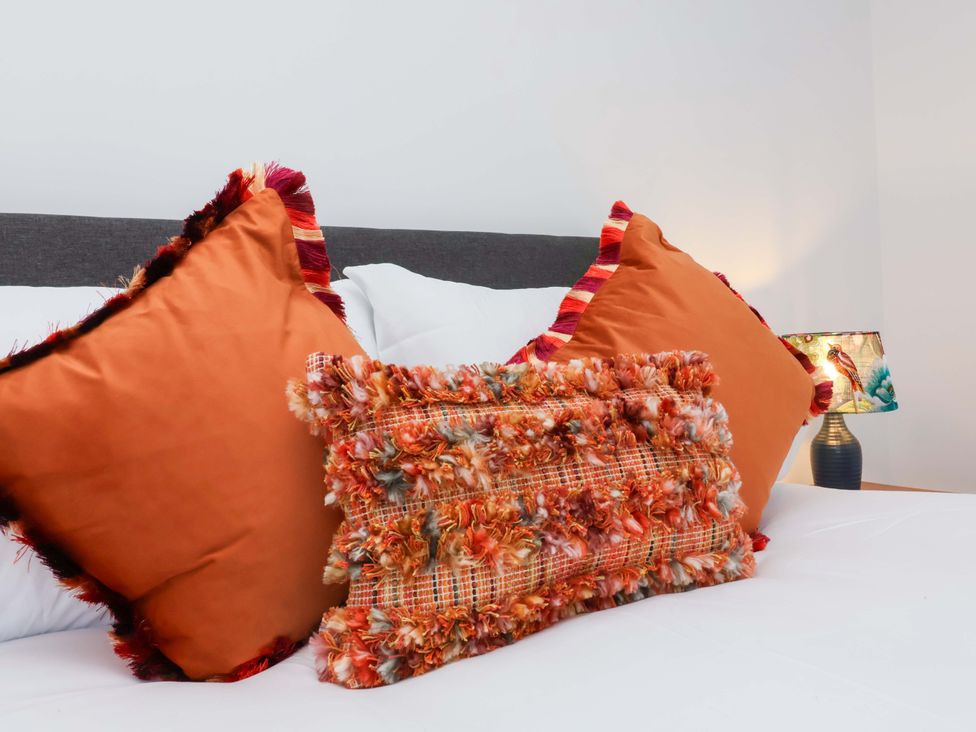 A bed with decorative pillows and a lamp at Hedgehog Highway, Parkham