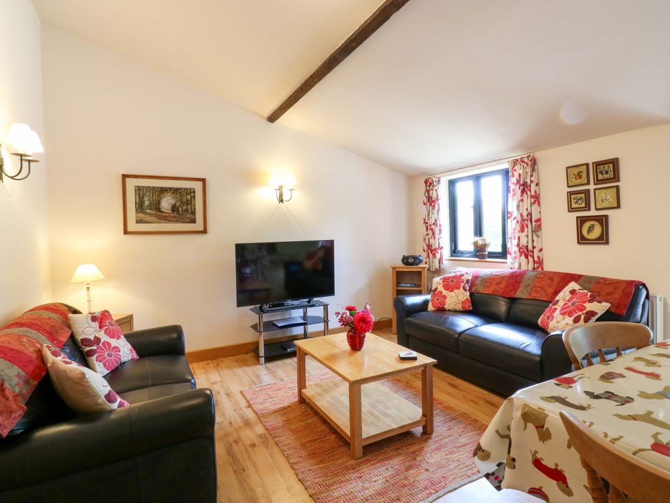 A living room with a sofa, television, and coffee table at The Golden Cross in Mendham near Harleston