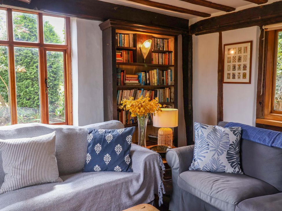 A living room with a sofa and bookshelf at Keirs Cottage in Carlton Colville