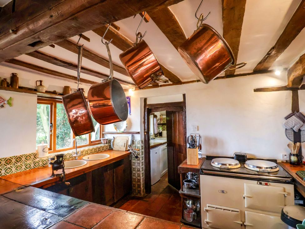 A kitchen with copper pots hanging and sinks at Keirs Cottage in Carlton Colville