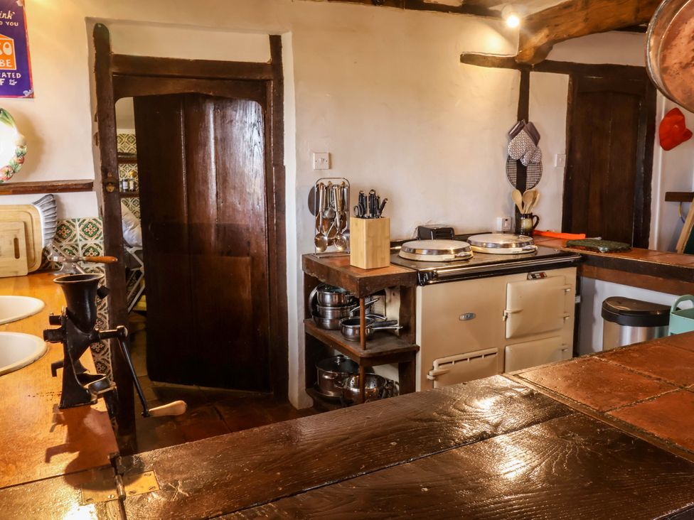 A kitchen with a cooking stove and wooden furniture at Keirs Cottage in Carlton Colville