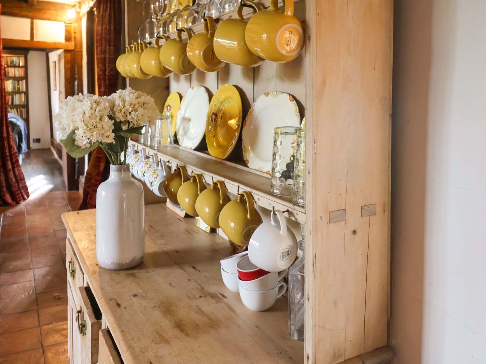 A kitchen shelf with dishes and flowers at Keirs Cottage in Carlton Colville