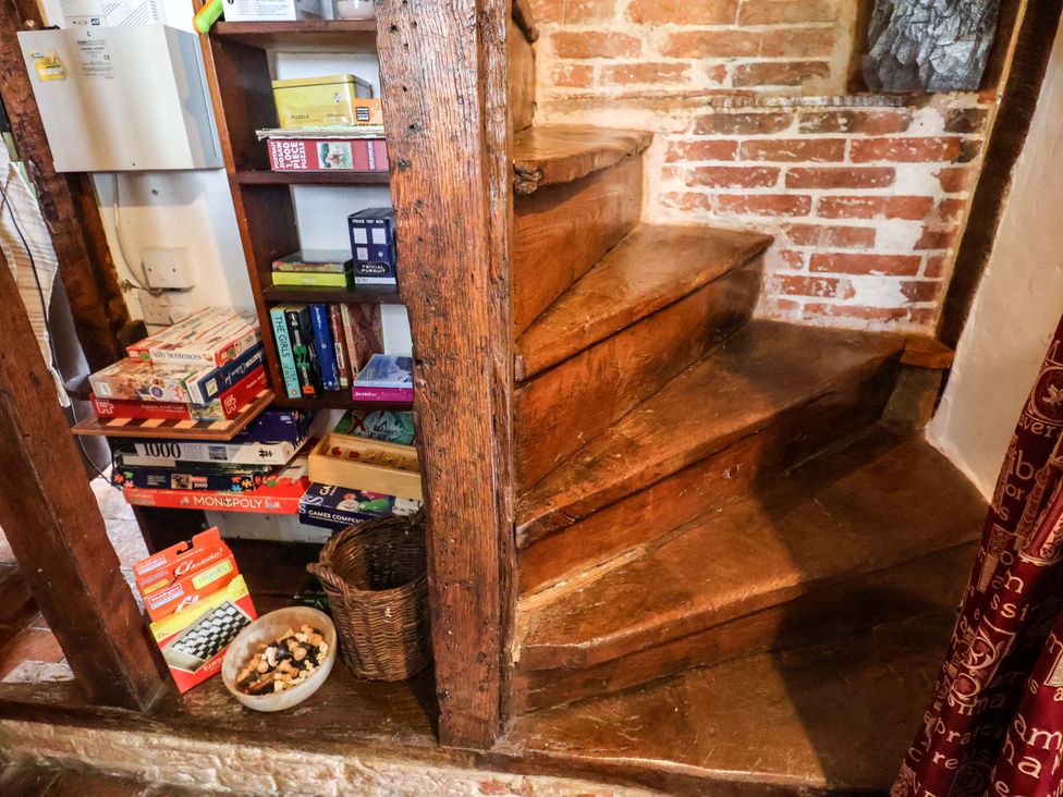A staircase and a bookshelf with board games at Keirs Cottage in Carlton Colville