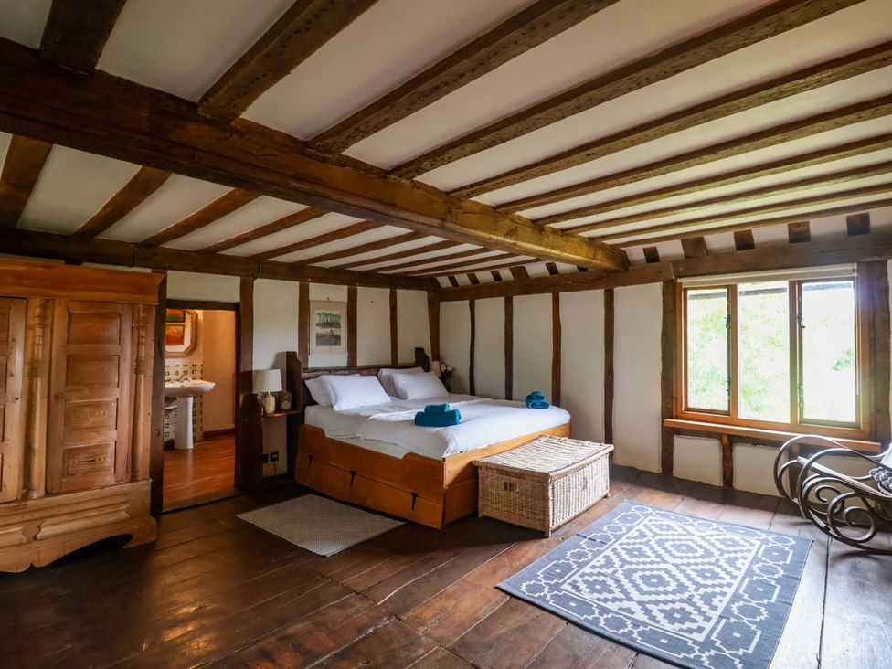A bedroom with a bed and armchair at Keirs Cottage in Carlton Colville