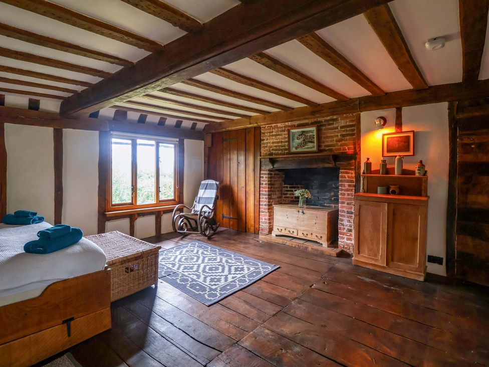 A bedroom with a bed and rocking chair at Keirs Cottage in Carlton Colville
