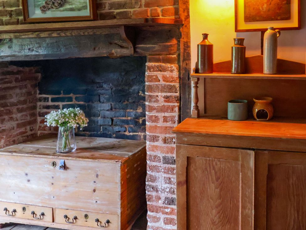 A living room with a wooden chest and vase on a shelf at Keirs Cottage in Carlton Colville