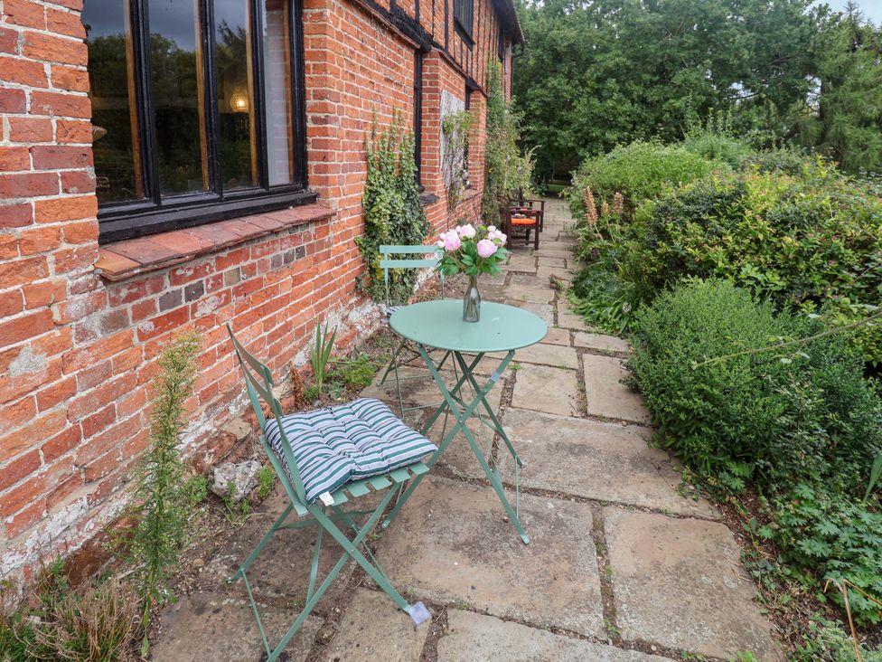 A garden with a table and chair near a brick wall at Keirs Cottage in Carlton Colville