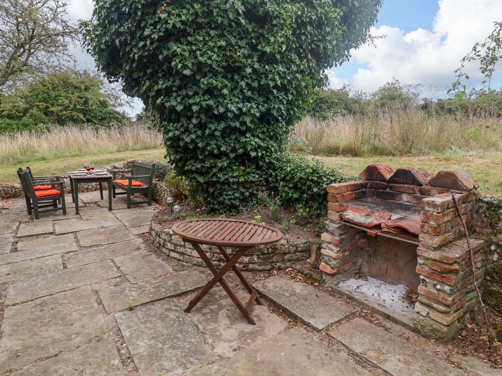 An outdoor area with a table and chairs beside a barbecue at Keirs Cottage in Carlton Colville
