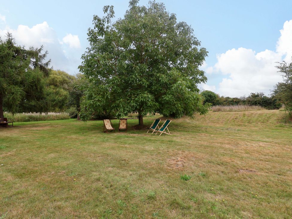 A garden with deck chairs under a tree at Keirs Cottage in Carlton Colville