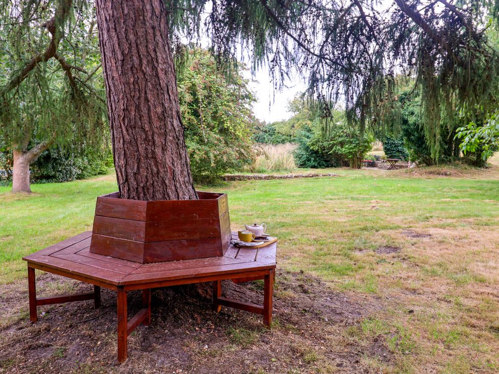 A wooden table around a tree with a tea set at Keirs Cottage Carlton Colville
