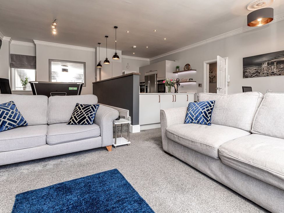 A living room with sofas and kitchen area visible at The Crows Nest in Buxton