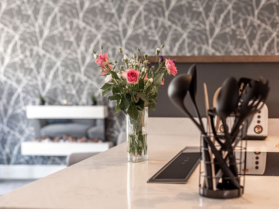 A kitchen with flowers in a vase and utensils on the counter at The Crows Nest in Buxton