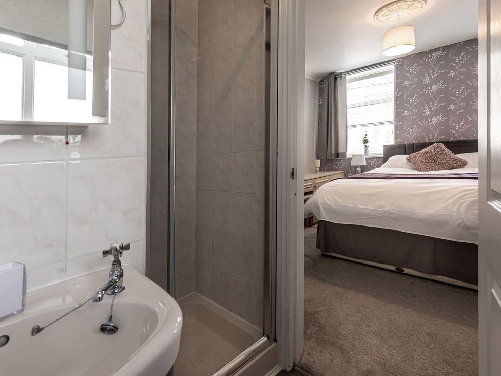 A bathroom with a sink and shower visible from a bedroom at The Crows Nest in Buxton