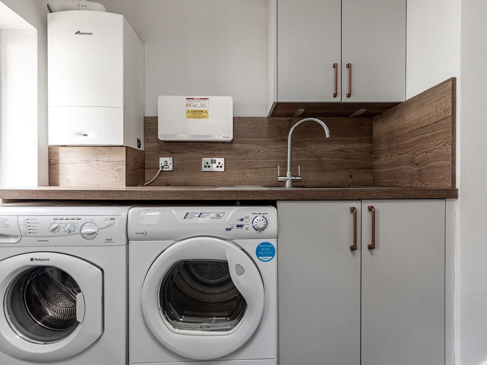A laundry room with a washing machine, dryer, and sink at The Crows Nest in Buxton