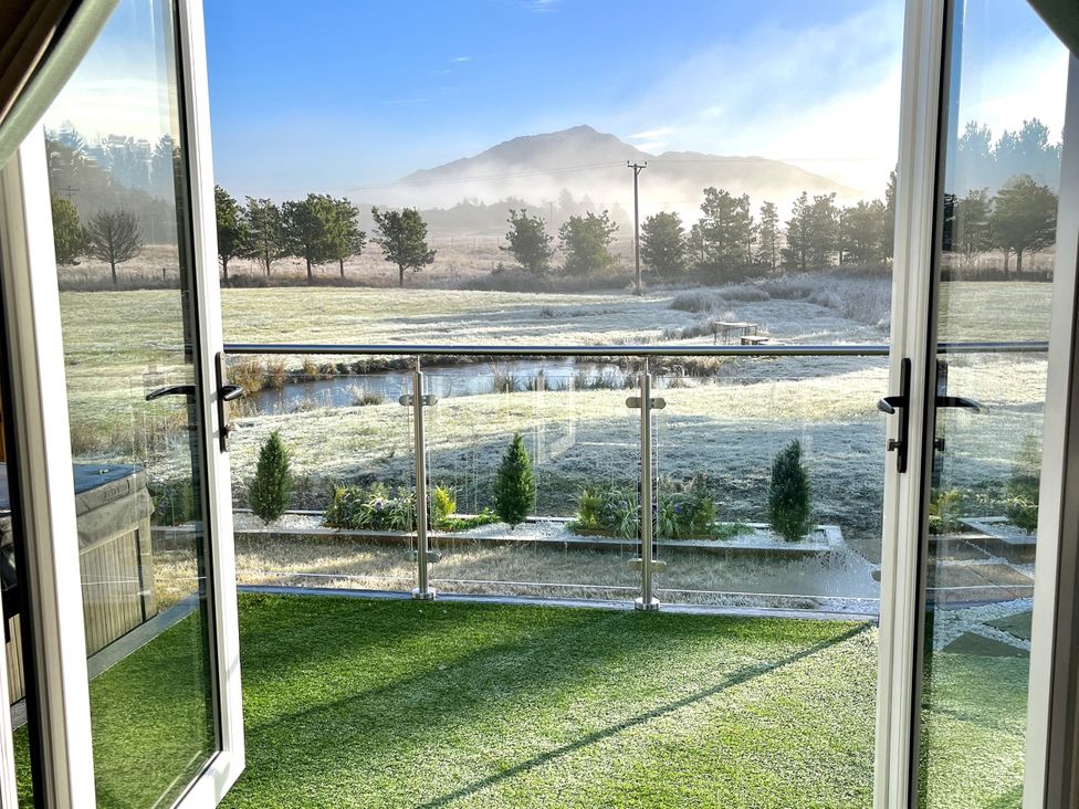 A view from a balcony showing trees and a pond at Crofters Suite