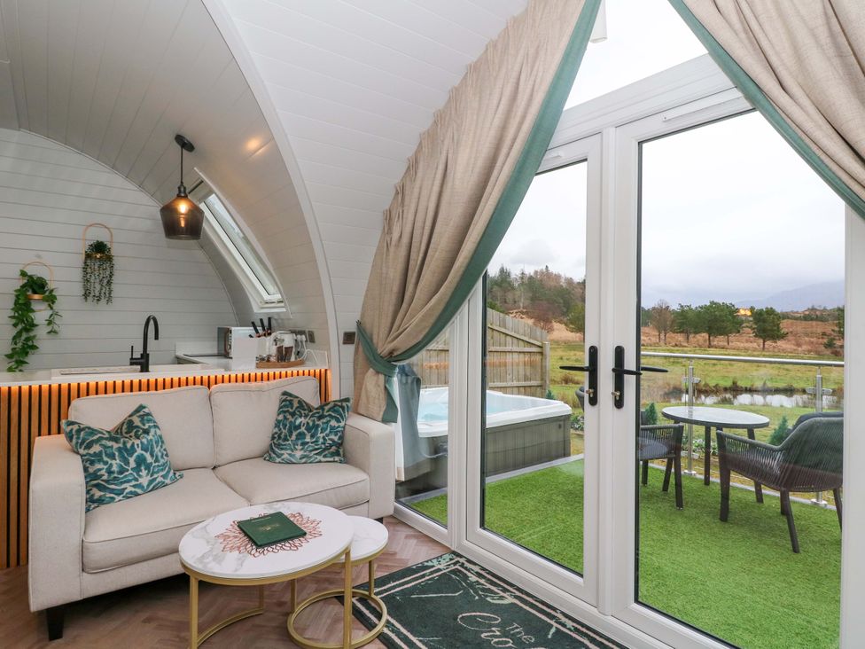 A living room with a sofa and kitchen area at Crofters Suite