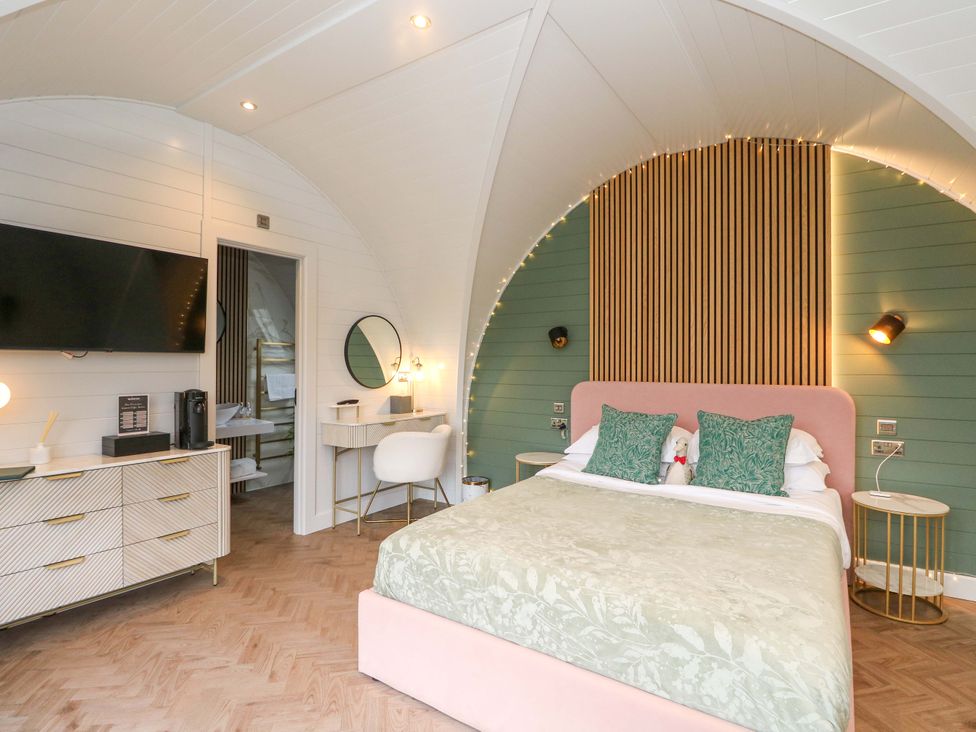 A bedroom with a bed, tv, and desk at Crofters Suite